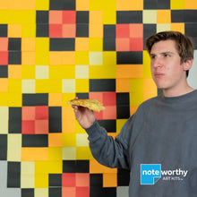 Load image into Gallery viewer, man eating pizza in front of large post it note wall mural pixel art
